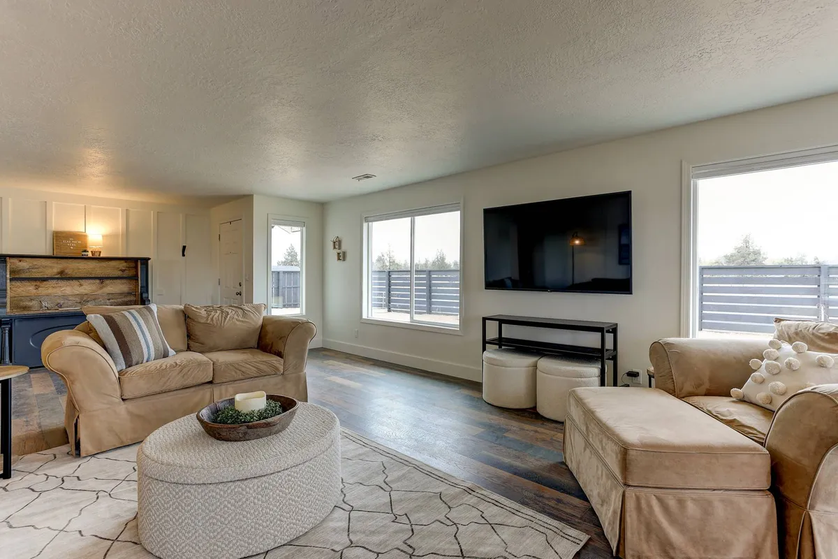 A spacious living room with comfortable sofas, a TV setup ideal for unwinding, and large windows that connect the interior to the serene outdoors. Decor is both classic and contemporary, blending comfort with historic touches.