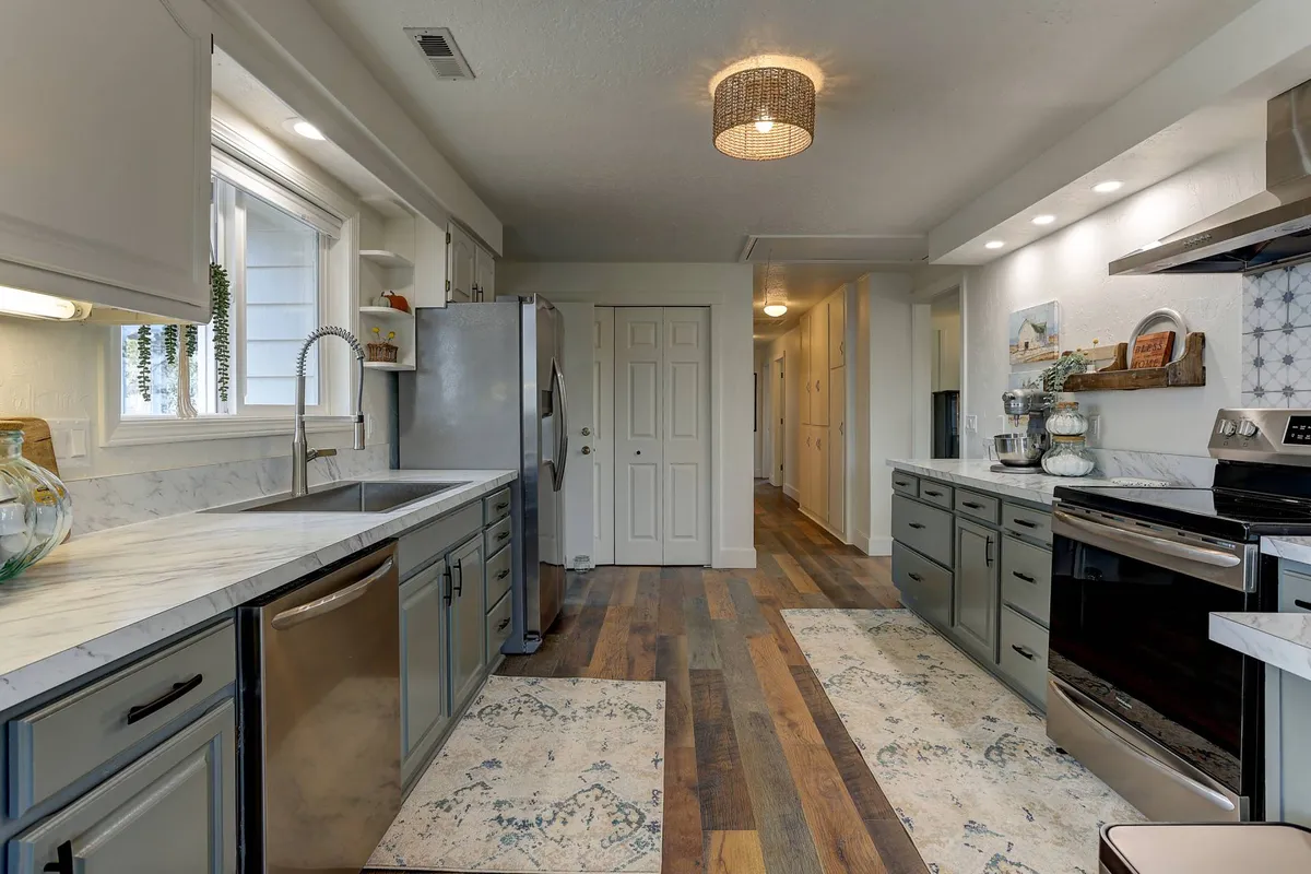 A functional, stylish kitchen with stainless steel appliances, marble countertops, wooden flooring, and decorative wall art. The space is set for cooking, entertaining, and gathering, emphasizing culinary activity and togetherness.